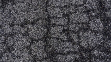 Top view of an old asphalt road in wet cracks. Worn road with cracks texture.