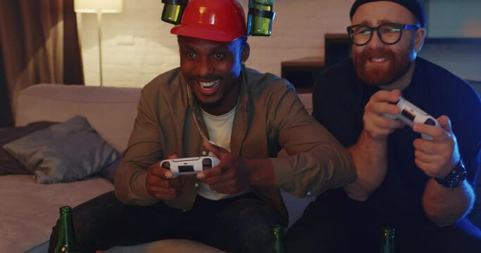 Happy Adult Men Friends Smiling and Playing Video Games using PlayStation. Handsome Multinational Two Friends spending Free Time holding Joystick spending fun time together. Controllers. Game Play.