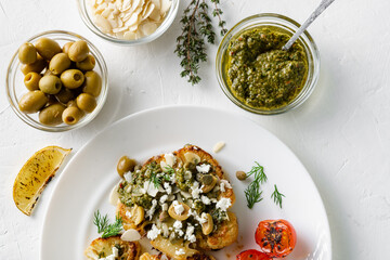 Vegetarian food concept. Cauliflower steak with spices, chimichurri sauce, almond flakes, olives, fried cherry tomatoes and capers on a white plate. White background.