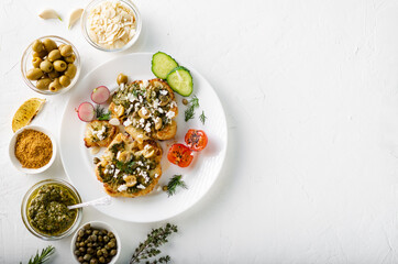 Vegetarian food concept. Cauliflower steak with spices, chimichurri sauce, almond flakes, olives, fried cherry tomatoes and capers on a white plate. White background.