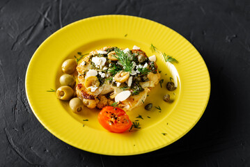 Baked cauliflower steak with chimichurri sauce, almond flakes, capers on a yellow plate. Vegetarian food. Alternative delicious food.
