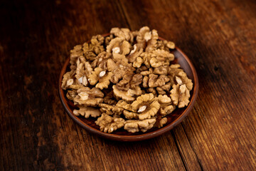 Peeled walnuts on a plate. Dark wooden background. Vegetarian, healthy food.