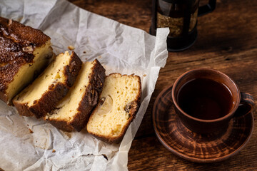 Banana bread sliced. Cup with herbal tea. Dark wooden background.