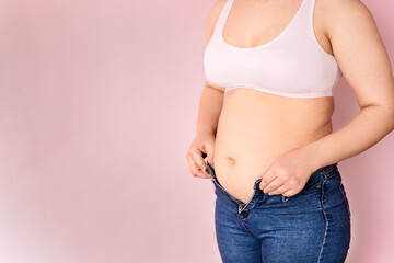 The concept of the diet is a close-up of women's hands that cannot fasten their trousers due to an...