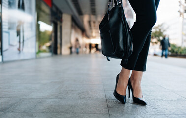 Close up shot of business woman's legs in black shoes standing on city street. Plenty of defocused...
