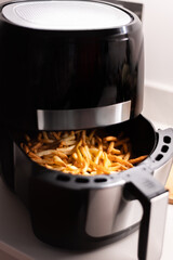 Air fryer with french fries on the worktop