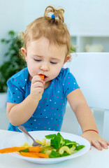 Child baby eats pasta with vegetables. Selective focus.