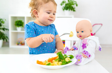 Child baby eats pasta with vegetables. Selective focus.