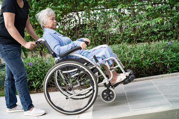 Caregiver help and care Asian senior or elderly old lady woman patient sitting on wheelchair at nursing hospital ward, healthy strong medical concept