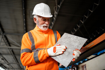 Factory production line worker checking roughness of ceramic tile product.