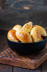 Potato stuffed hand pies in a black bowl on a wooden board.