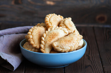 Freshly fried hand pies with meat in a bowl on a wooden background. Close up. - 487148693