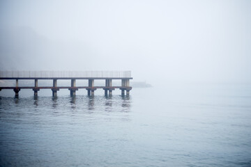 Pier, mooring in fog on the sea against the backdrop of mountains