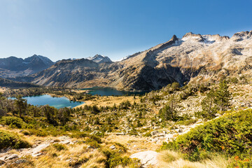 Fototapeta na wymiar Panorama de lacs de montagne au pied de pics découpés sur fond de ciel bleu en automne. Lacs d'Aubert et d'Aumar, Hautes Pyrénées, réserve du Néouvielle.