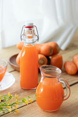 Carrot and glass of fresh juice on wooden background
