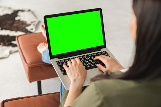 Mockup blank green screen on laptop. Back view portrait of a businesswoman student freelancer tutor teacher having video call conference on laptop computer at home on distance.