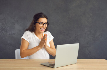 Excited young Caucasian woman in glasses sit on desk triumph with online lottery win on laptop....