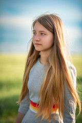 Portrait of a beautiful young girl in a summer field outside the city.
