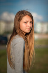 Fototapeta premium Portrait of a beautiful young girl in a summer field outside the city.