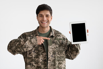 Positive military man showing digital tablet with empty screen