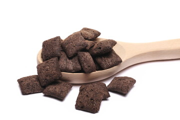 Cereal flakes in form of pillows, with vanilla flavor, pile in wooden spoon isolated on white