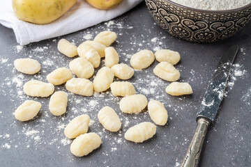 Fototapeta na wymiar Uncooked italian pasta gnocchi over stone background with copy space