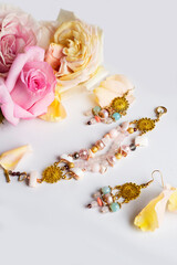 golden  jewerly bracelet and earning with semiprecious and roses petals at white background