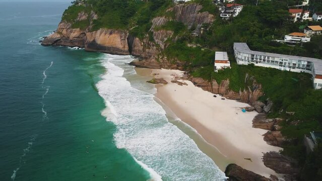 Aerial view of Praia da Joatinga, a paradise in Rio de Janeiro, Brazil. Sunny day with some clouds in the morning. Sea with good waves for surfers. Greenish sea. Drone take.