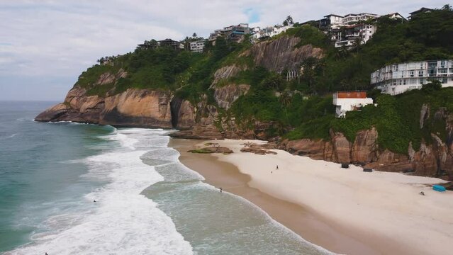 Aerial view of Praia da Joatinga, a paradise in Rio de Janeiro, Brazil. Sunny day with some clouds in the morning. Sea with good waves for surfers. Greenish sea. Drone take.