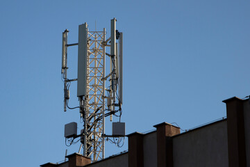 Telecommunication tower of 4G and 5G cellular. 5G radio network telecommunication equipment with radio modules and smart antennas mounted on a metal. Blue sky in the background. Located on the roof.