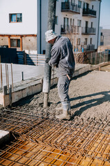 Mason building and worker using a automatic cement pump and levelling a layer of fresh concrete floor at house, construction site