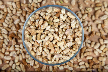 Dried mulberry in glass bowl on wooden background