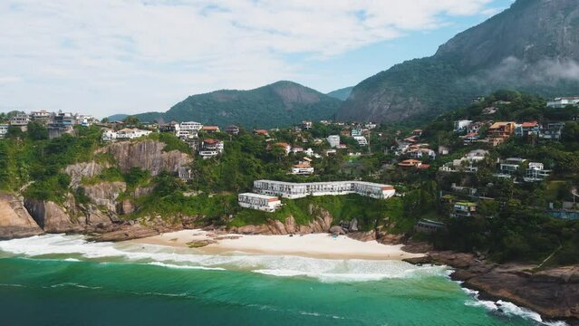 Aerial view of Praia da Joatinga, a paradise in Rio de Janeiro, Brazil. Sunny day with some clouds in the morning. Sea with good waves for surfers. Greenish sea. Drone take.