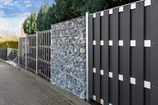 Modern gabion wall system with stones as element of garden or house wooden metal fence.