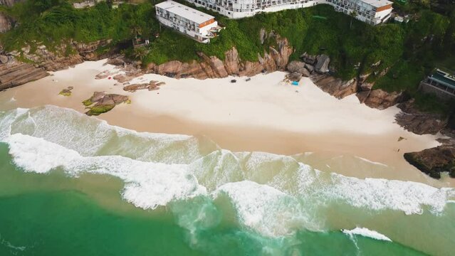 Aerial view of Praia da Joatinga, a paradise in Rio de Janeiro, Brazil. Sunny day with some clouds in the morning. Sea with good waves for surfers. Greenish sea. Drone take.