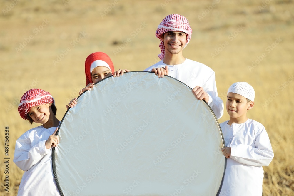 Wall mural Arabic family in nature holding copy space banner