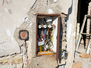 Fototapeta na wymiar Abandoned and dismantled building. Close-up view of an open cabinet with electricity.