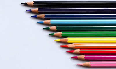 Color pencils on a light gray blue background. Top view with space for text. Back to school concept. Flat lay stationery mockup. Bright backplate for your design. Spectrum of different colors