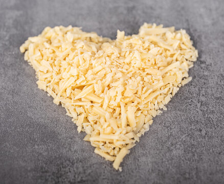 Grated cheese arranged in heart shape on gray background