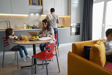 Woman working with laptop and reaching to her daughter