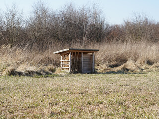 Wooden feeder for pheasants and partridges in the meadow.