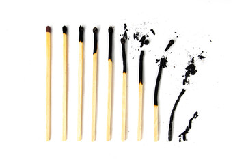 Different stages of match burning. A row of burnt matches, from almost a whole match to a completely burnt match to the dust. White background, flat lay.