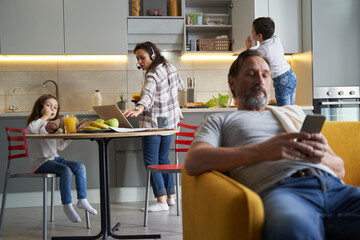 Female cooking and working at laptop in kitchen