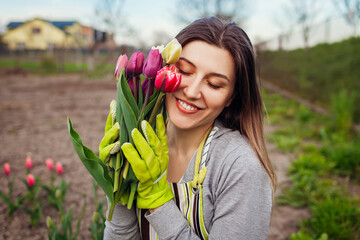 Gardener picked bouquet of fresh tulips in spring garden. Young happy woman smiling holding flowers