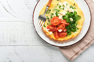 Rustic omelette or frittatas with green onions, cheese mozzarella, green arugula and tomatoes on old wooden white background. Healthy food concept. Breakfast. Copy space. Top view. Mock up.