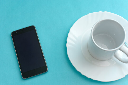 Plate, cell phone and cup on blue background.