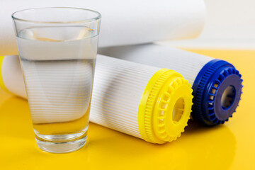 A glass of clean water next to the water purification filter. The concept of a household filtration system