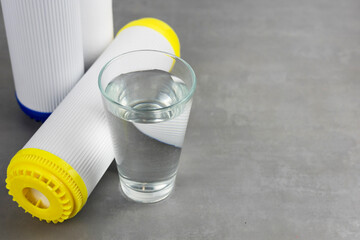 A glass of clean water next to the water purification filter. The concept of a household filtration...