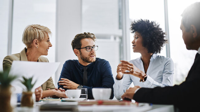 Give us difficult and well show you easy. Shot of a group of businesspeople sitting together in a meeting. - Powered by Adobe