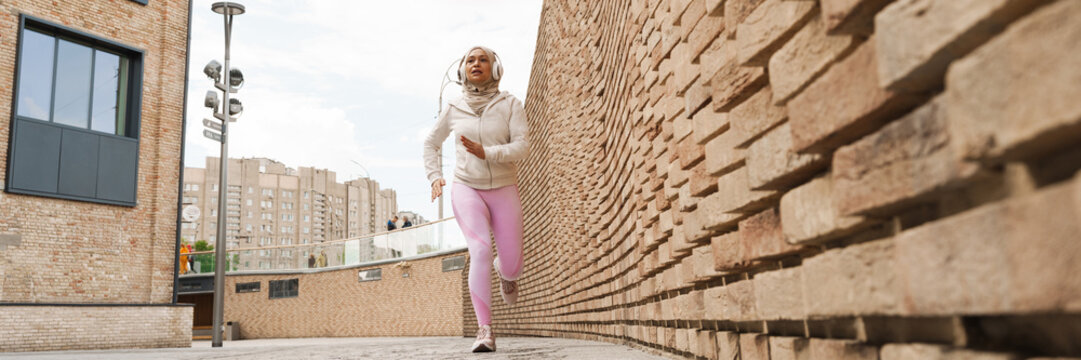 Middle Eastern Woman In Hijab Listening Music With Headphones And Running